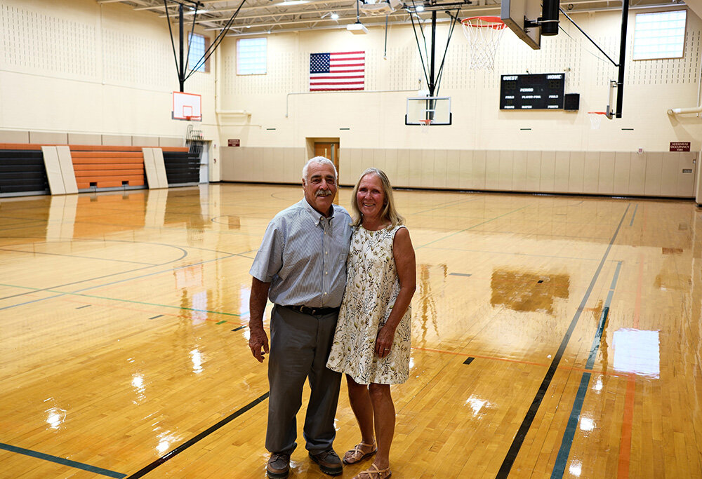 Benjamin and Susan Trapani stand inside the elementary school gymnasium that has been named in his honor.